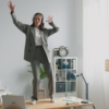 Woman in suit dancing on desk with headphones
